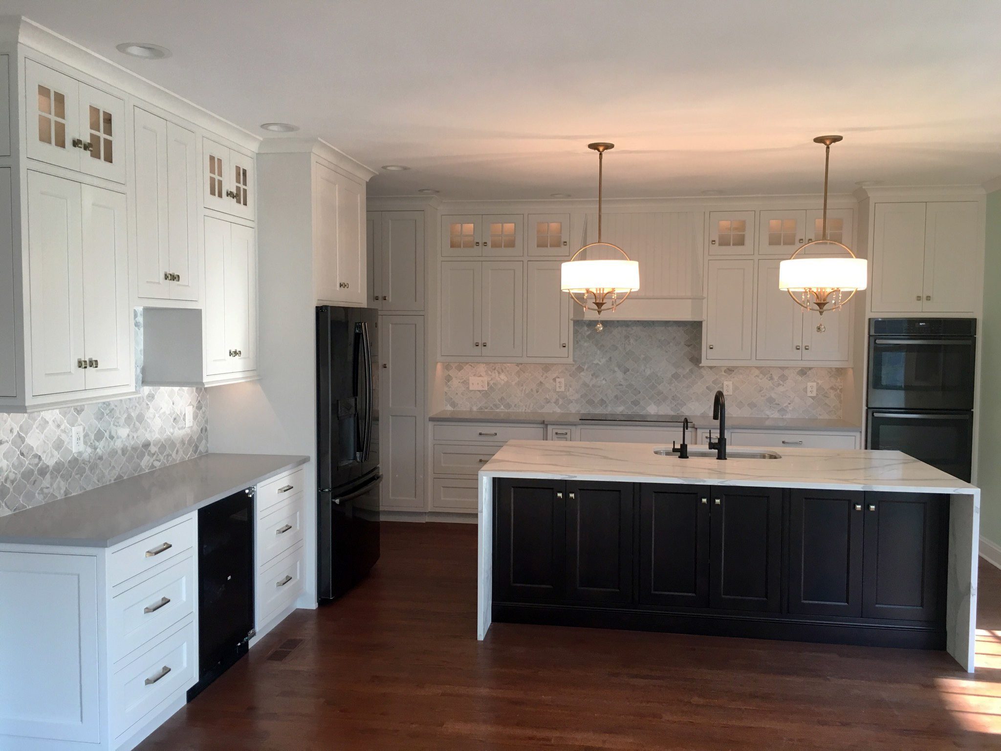 Bethany Beach Home Kitchen features White Cabinets and a Black Island