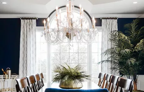 Wood Dining Room Table and Chairs with a Chandelier above in a Navy Blue Dining Room Design